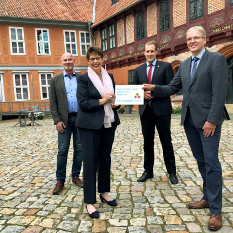 Ministerin Birgit Honé übergibt den Bescheid an Landrat Jens Böther vor dem Bleckeder Schloss.